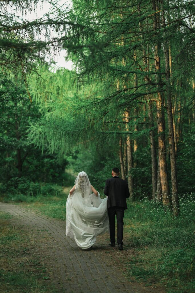 A couple walking away down a path through tall woodland
